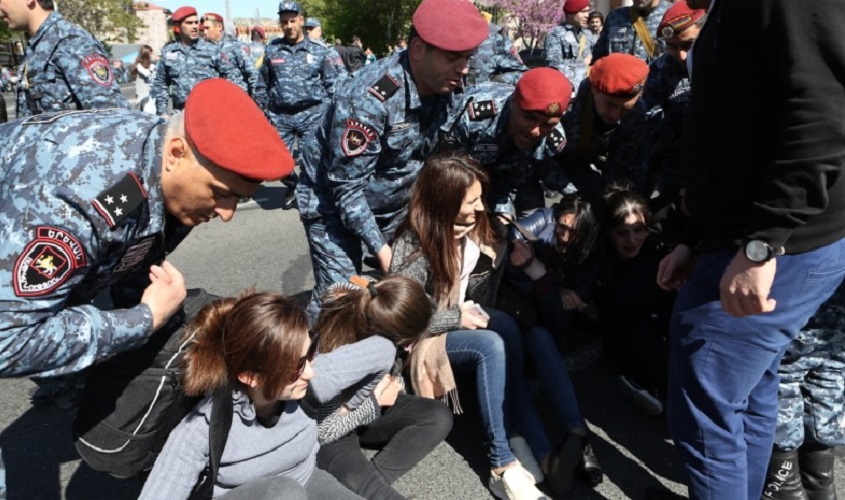 Young women blocking the streets, surrounded by police or soldiers.