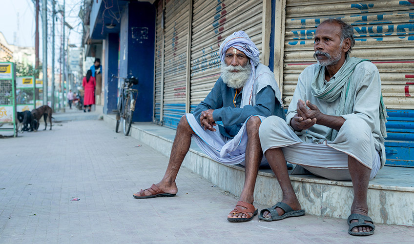 Two men sitting on a step outside a shop