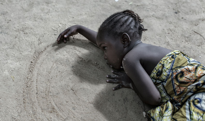 Young girl draws pictures in the sand