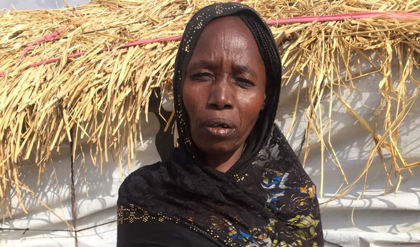 Portrait of Maryamu standing outside a dwelling at the IDP camp