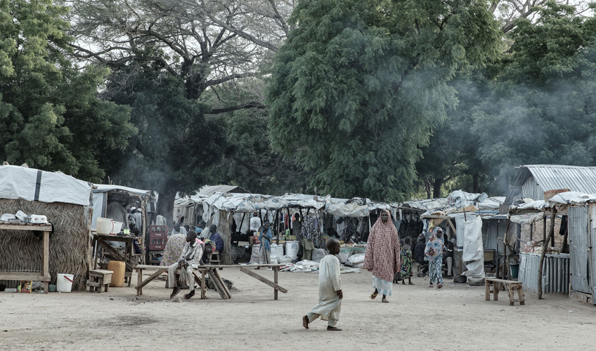 Displacement camp with people walking and sitting in the foreground.