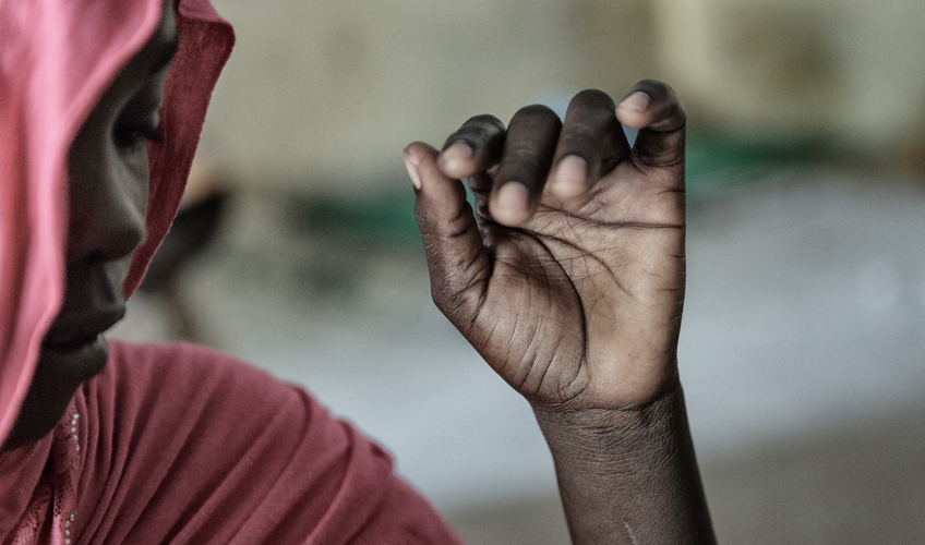 Close up of Jummai, wearing red, her face partially concealed by her head scarf.