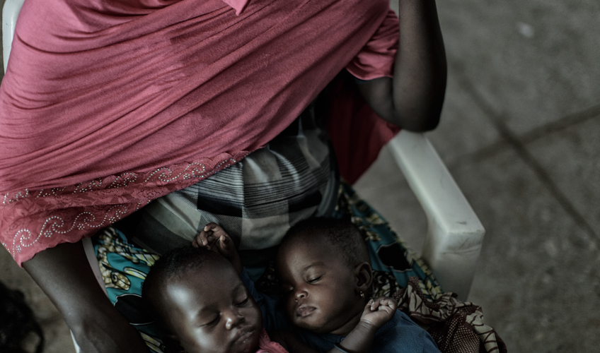 Twin babies asleep on Jummai's lap.