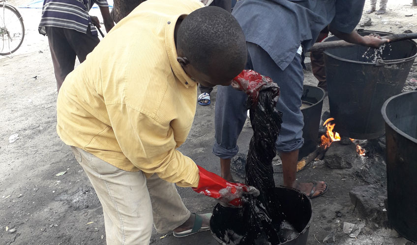 A man tie dyes fabric in a bucket. 