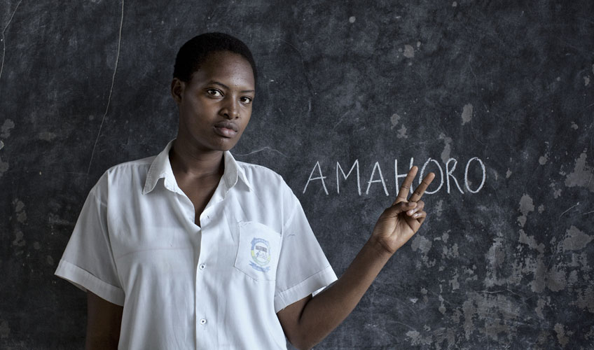 Young woman in front of blackboard making the peace sign with her fingers