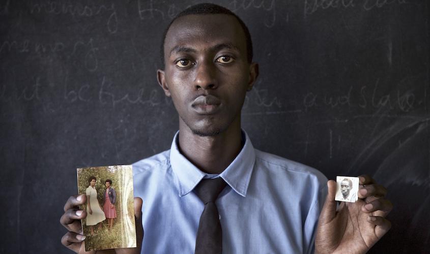 Portrait of young man holding old photos.