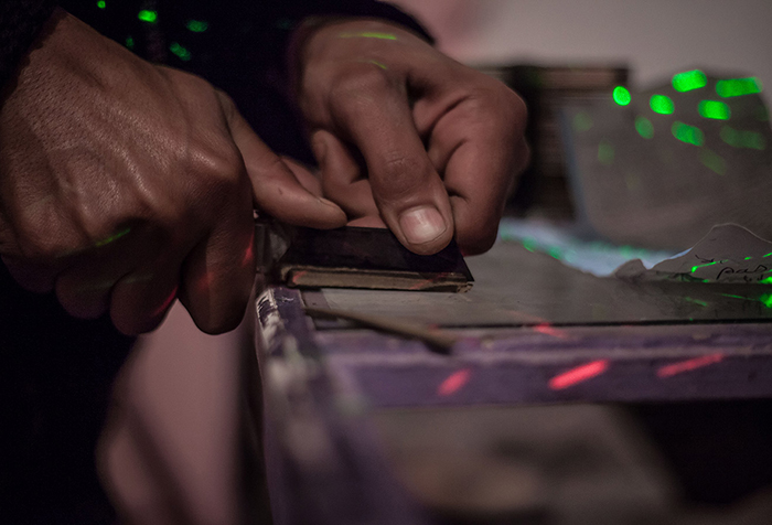 A close up of a man's fingers as presses down on an object as he cuts it