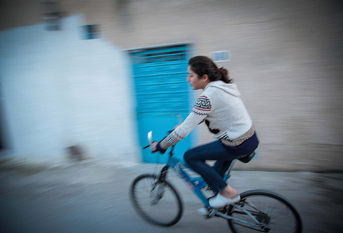 A young person cycles down the street past a blue door