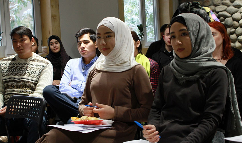 A group of women and men listen at a meeting in Kyrgyzstan