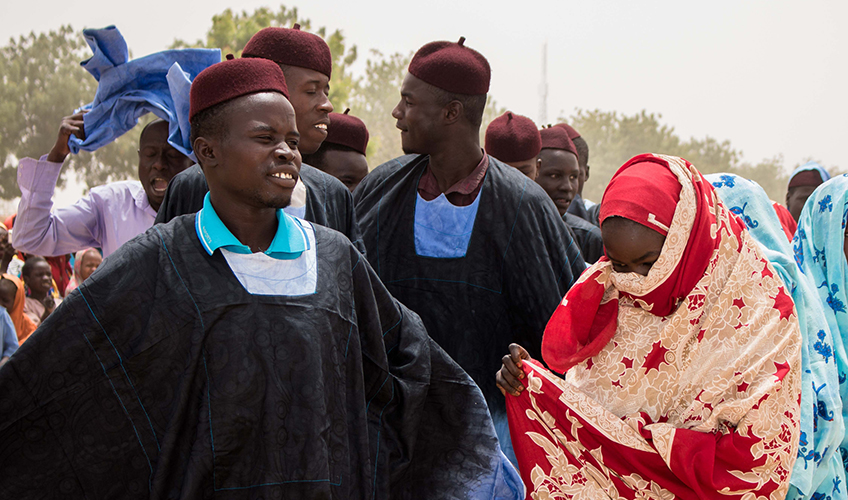 A group of African women and men stand together in traditional dress