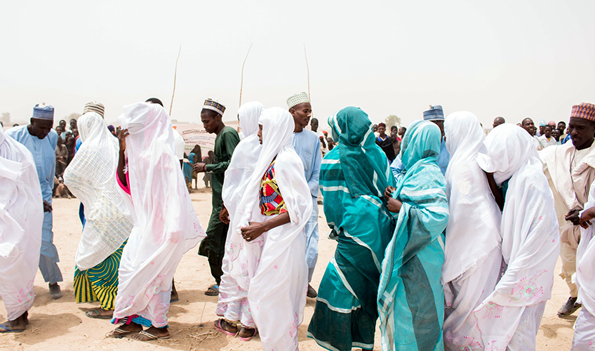 A group of African women and men dance in traditional dress