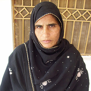 Magsood stands in front of a gate, looking at the camera with a serious expression