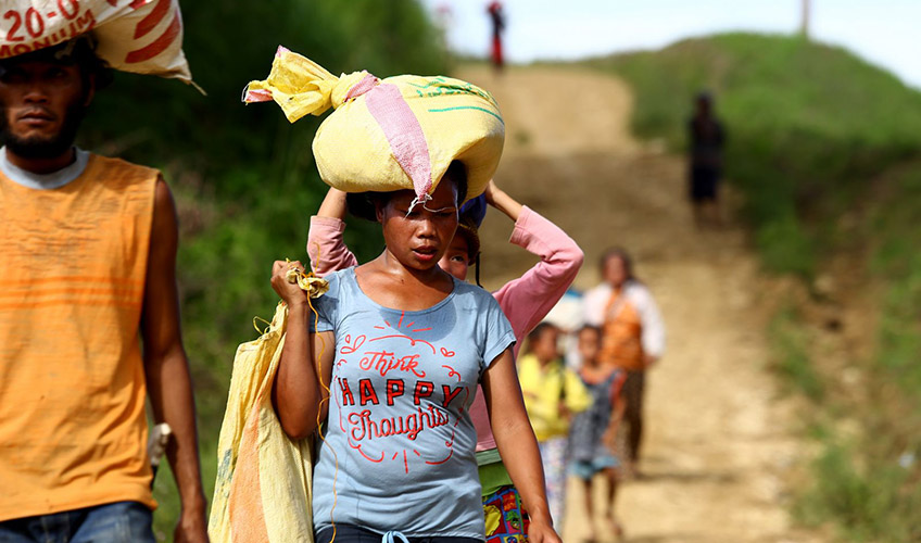 A Filipino woman and man walk along a dirt road 