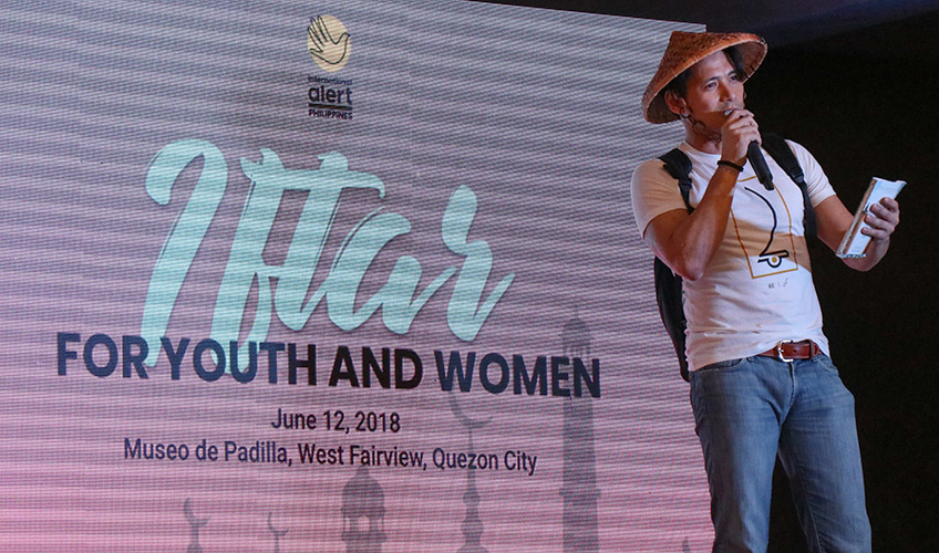 A Filipino man speaks at an event while wearing a traditional hat 