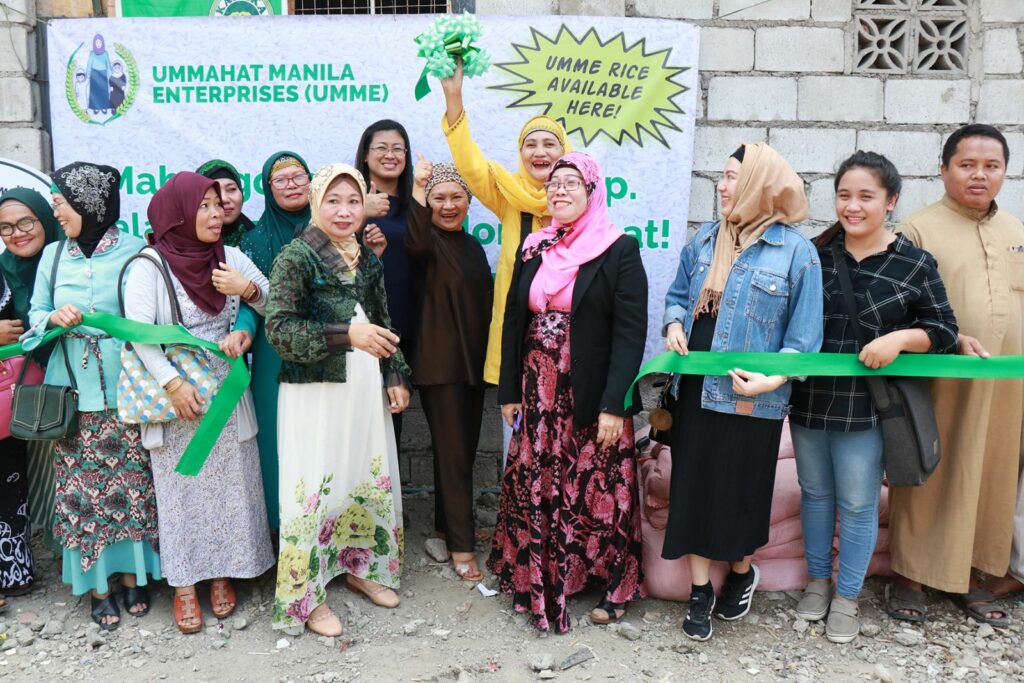 A group of Filipino women smile while a green ribbon is cut