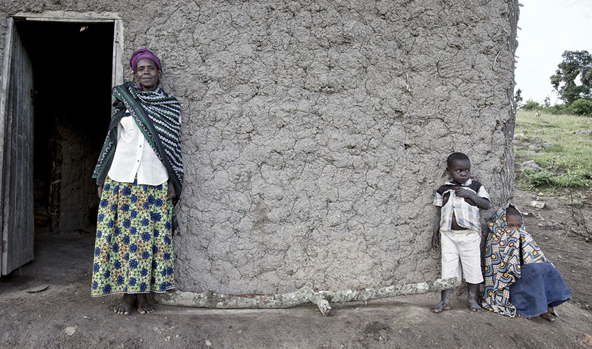 Monica standing outside her house, with two children nearby.