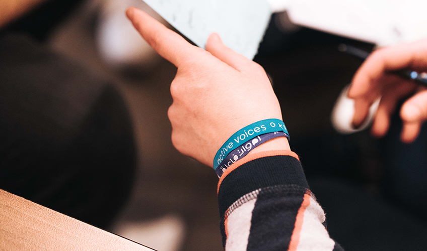 A person displays wrist bands in Arabic 