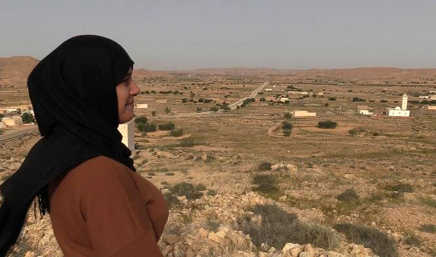 A Tunisian woman smiles as she looks over the countryside