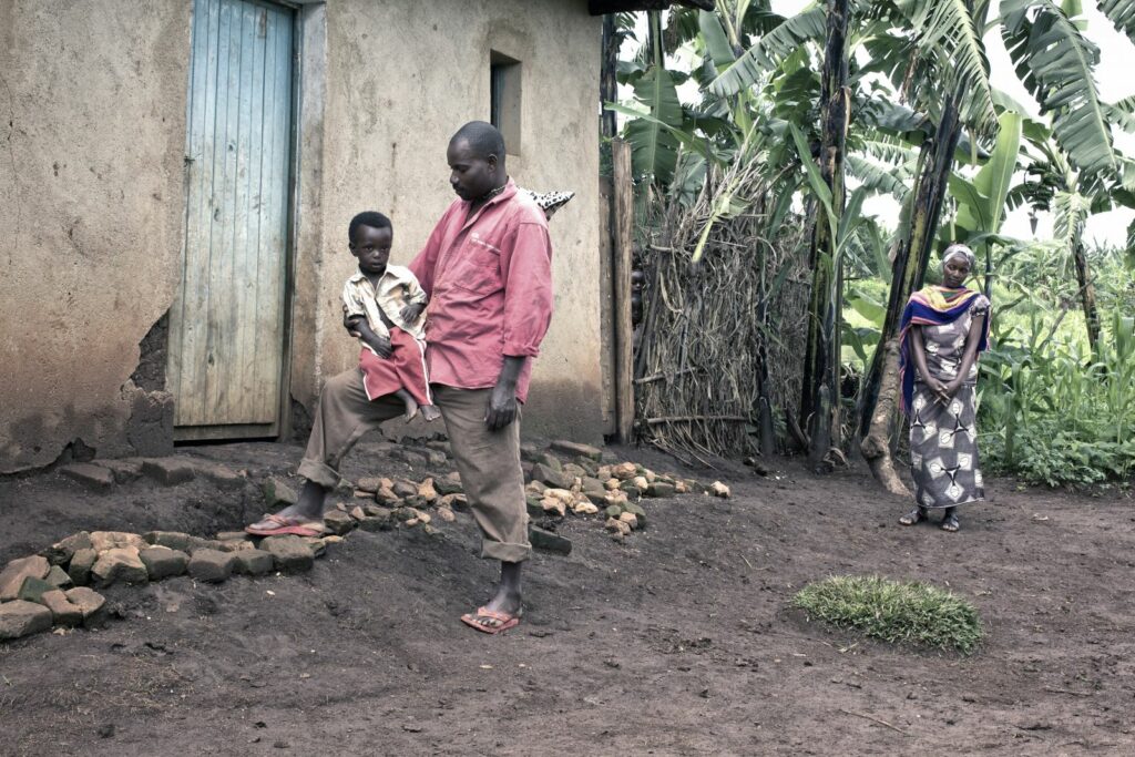 A middle aged man rests a young child on his knee as a woman looks on
