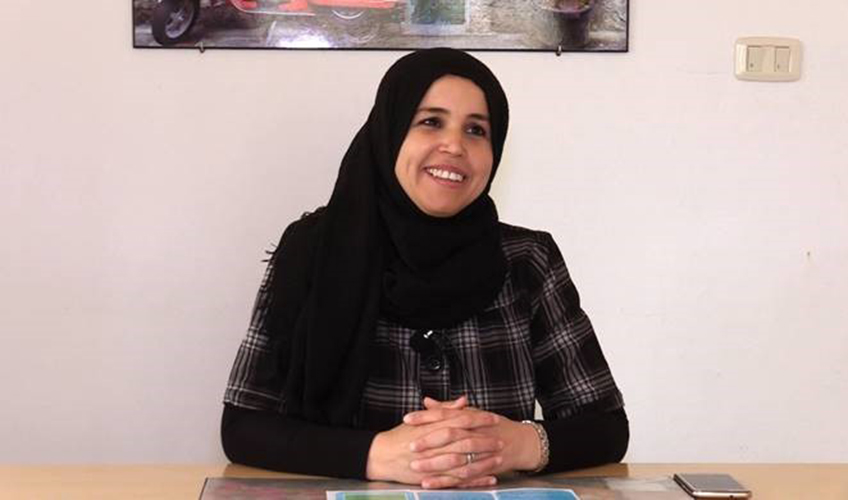 A Tunisian woman sitting behind a desk smiles at the camera
